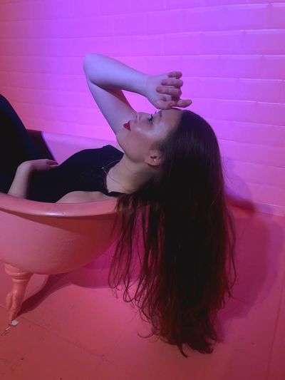 Thoughtful young woman reclining on pink chair