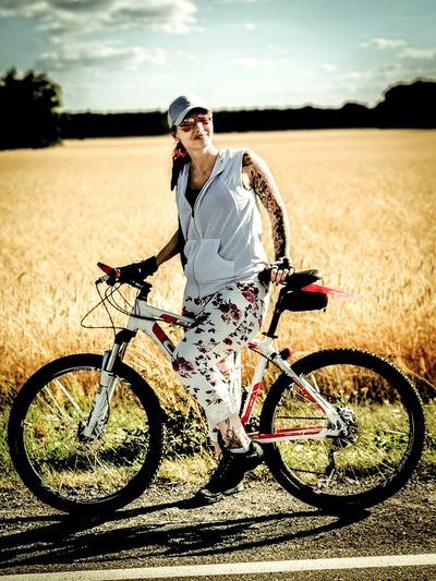Full length of woman standing with bicycle on field