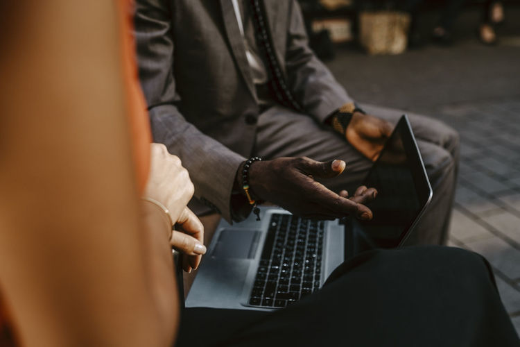 Cropped image of male entrepreneur discussing with female colleague over laptop