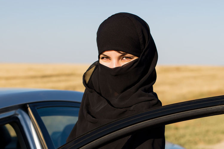 Islamic woman driver owner of car at open door. traditional islamic clothing