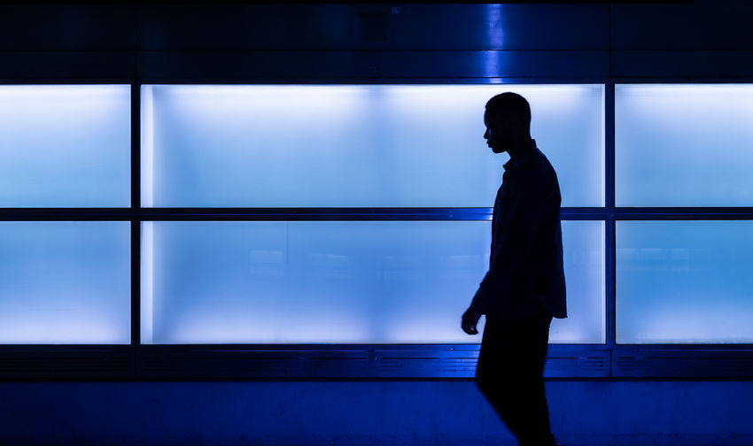 Side view of silhouette man standing against window