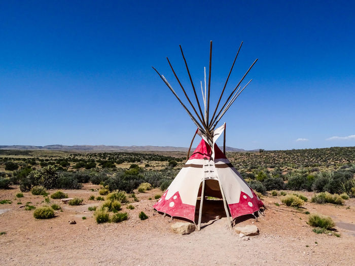 Traditional indian tent on field against clear blue sky