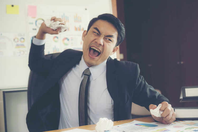 Angry businessman throwing paper balls in office