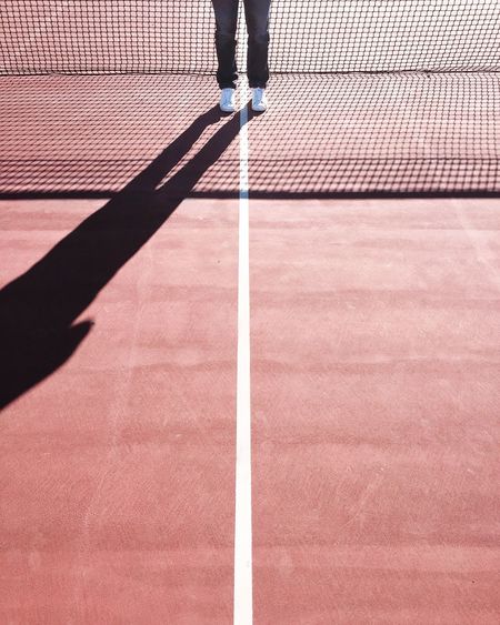 Low section of man standing on tennis court