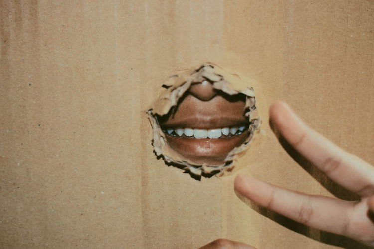 Man lips seen through torn cardboard