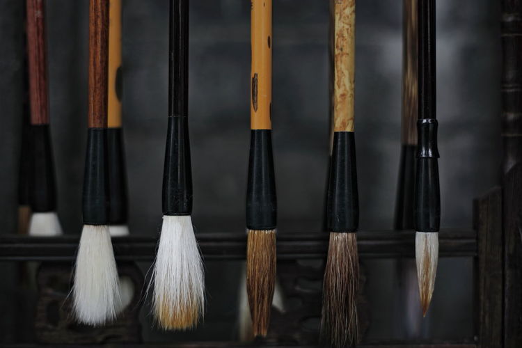 Close-up of paintbrushes hanging in row