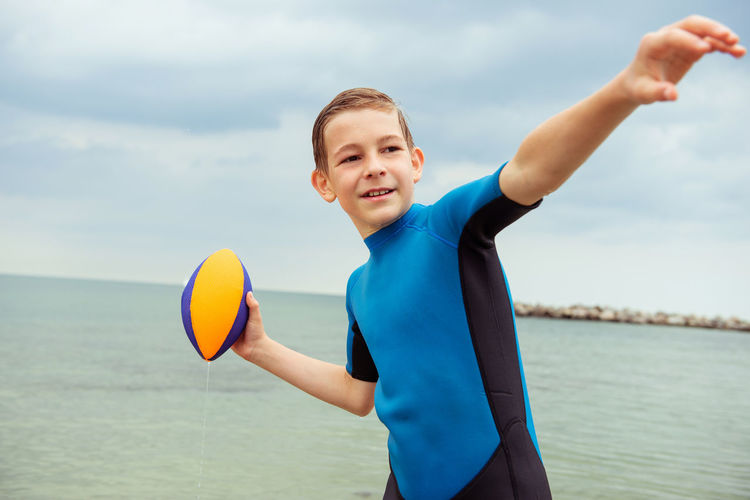 Happy playful boy playing with rugby ball in sea
