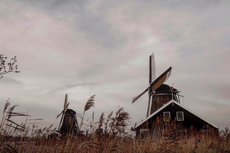 Low angle view of traditional windmill on field against sky