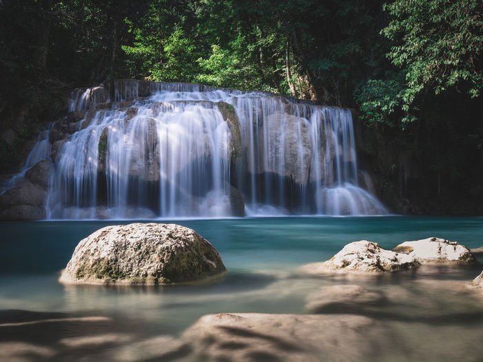 Scenic waterfall flowing water, turquoise pond in rainforest. erawan falls, kanchanaburi, thailand.