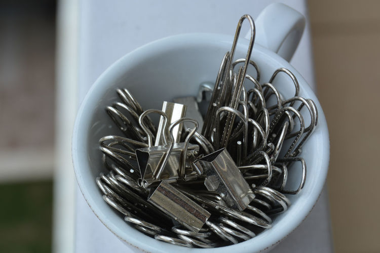 Portrait of a tiny cup filled with metal binder clips 