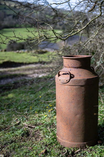 Close-up of rusty metal milk churn in a field 
