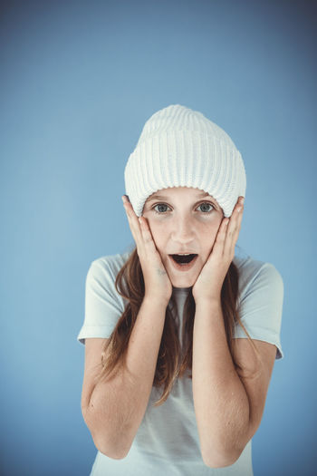Portrait of young woman wearing hat against blue background