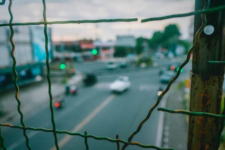 Close-up of fence by road in city