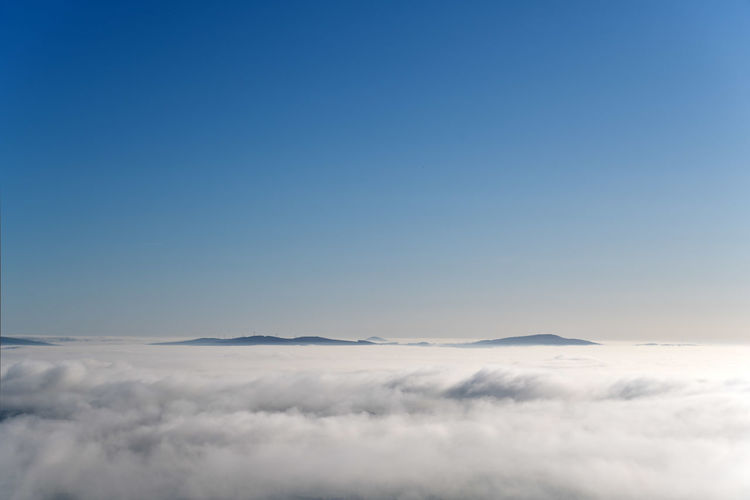 Low angle view from above the clouds looking at other mountain tops protruding through the clouds