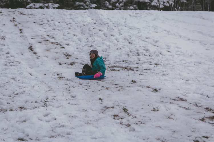 Girl sitting on snow covered land