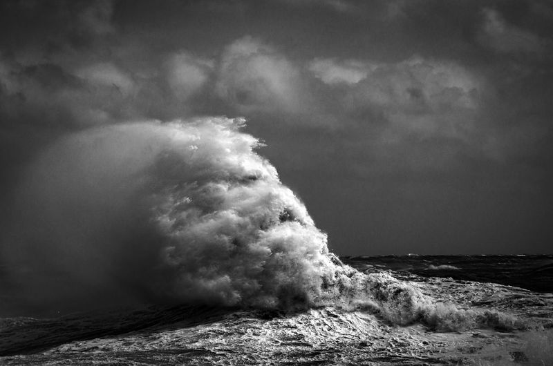 Sea waves rushing towards shore against sky