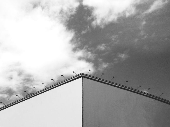 Low angle view of birds perching against cloudy sky