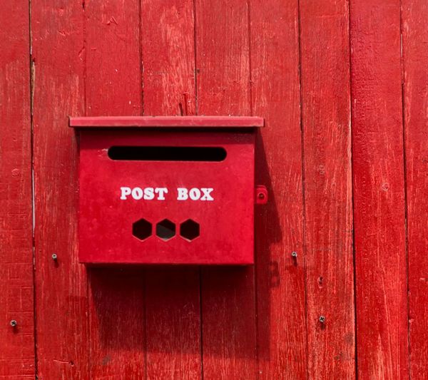 Red post box on wooden wall