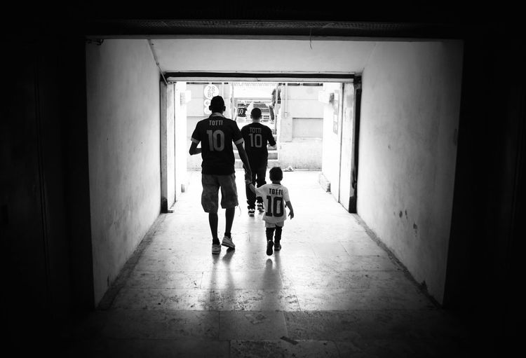 Rear view of father and son walking towards soccer stadium