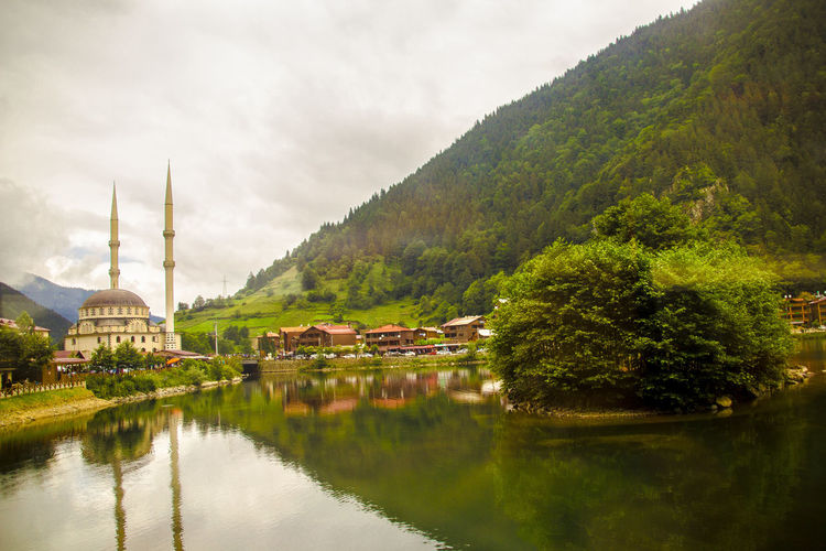 Scenic view of mosque by lake and mountain against sky