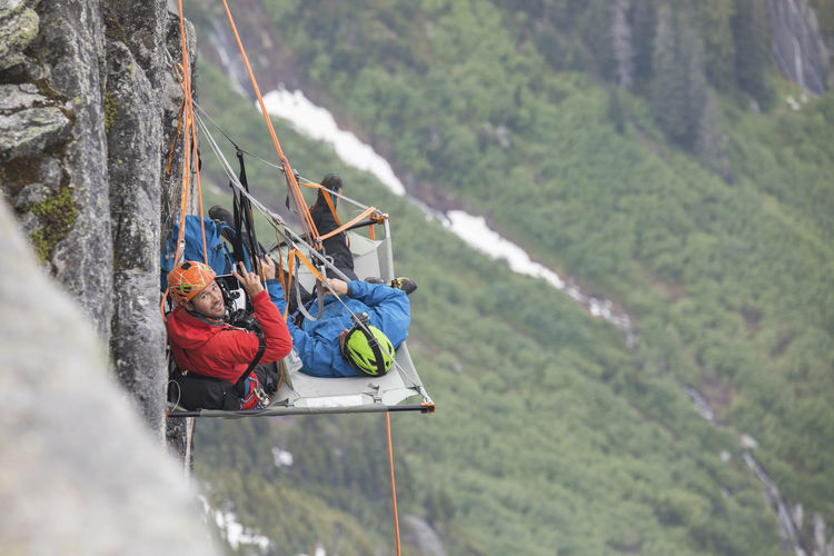 Portrait of rock climbers using portaledge during climbing trip.