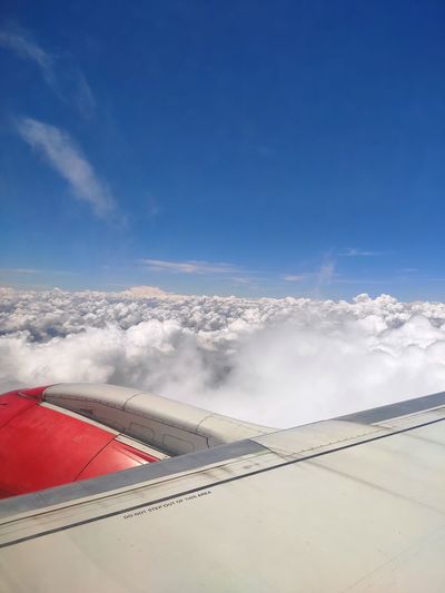 Airplane flying over clouds against blue sky