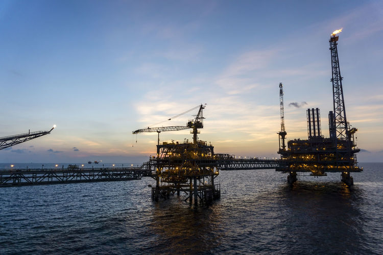 An oil productions platform connected with bridge during sunset at oil field 