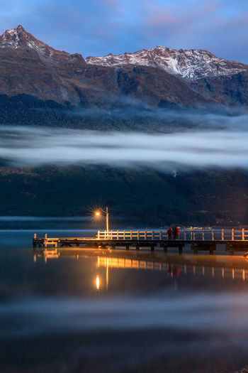 Scenic view of sea and mountains against sky at night
