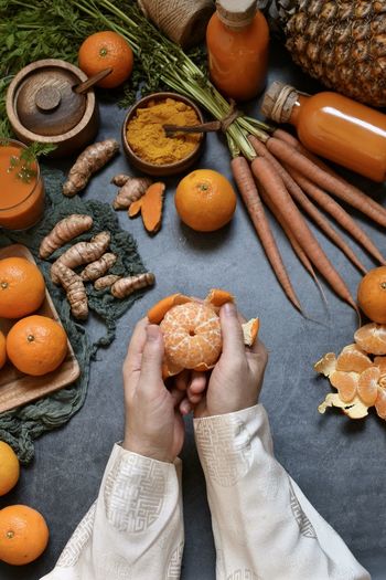 Cropped hands of person holding orange fruit on table