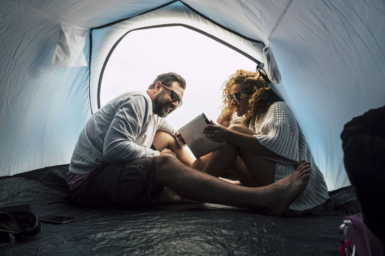 Smiling couple using digital tablet in tent