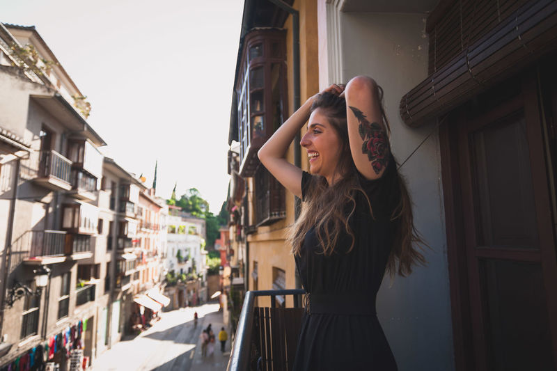 Smiling beautiful woman with hand in hair while standing in balcony