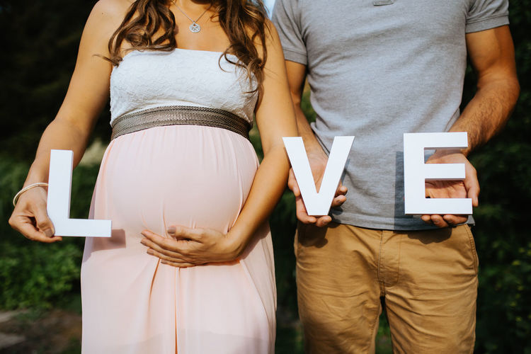 Midsection of man with pregnant woman holding love text