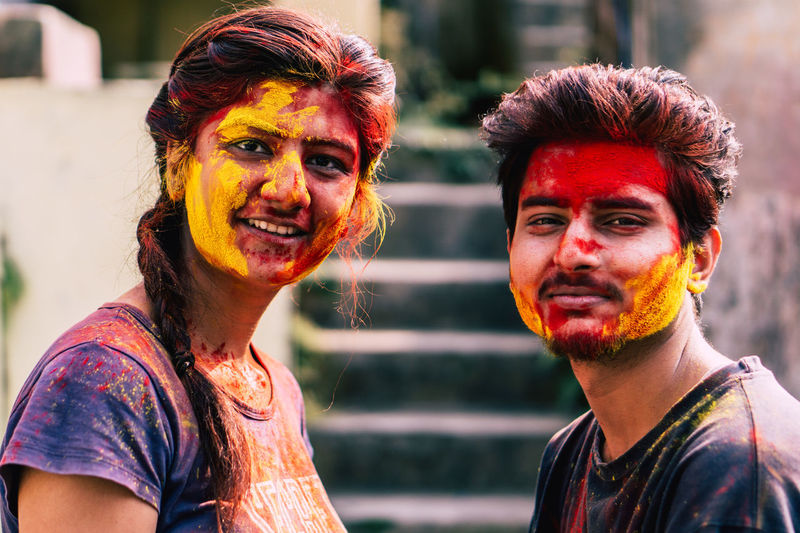 Portrait of smiling friends covered with powder paint while standing outdoors