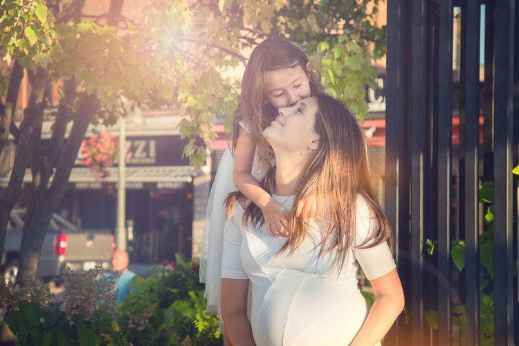 Happy daughter kissing pregnant mother at park
