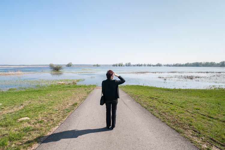 Rear view full length of woman standing against flooded road