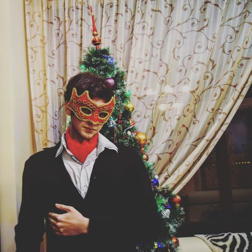 Portrait of man in mask by christmas tree