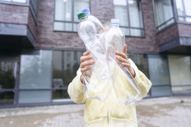 Girl holding empty plastics bottles on footpath