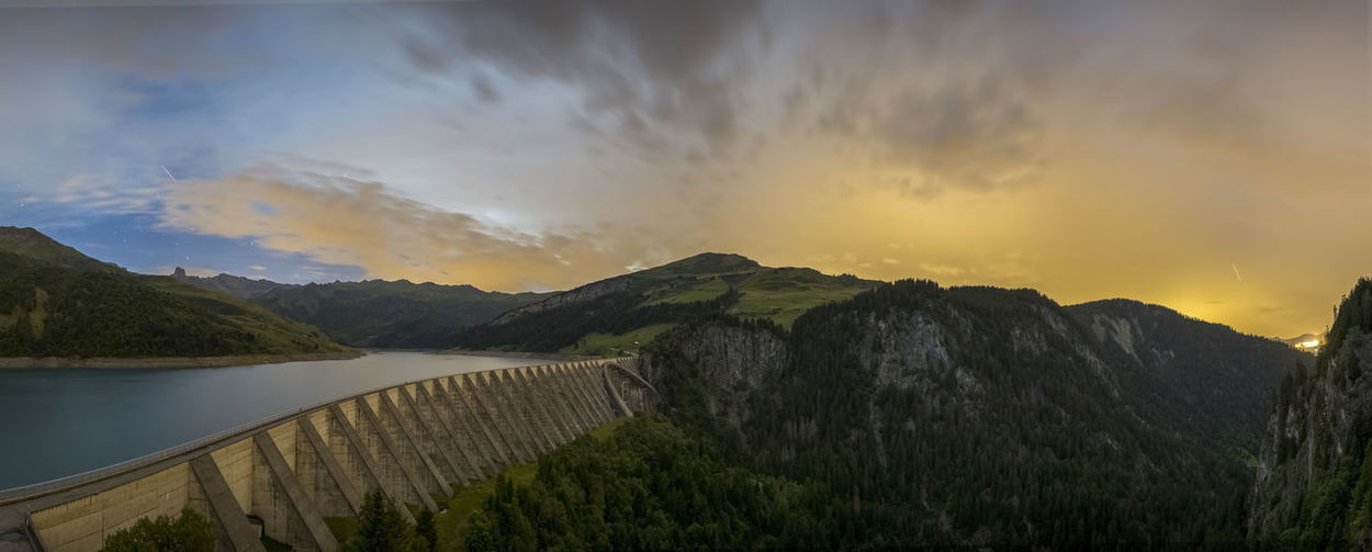 Panoramic view of river amidst mountains against sky during sunset