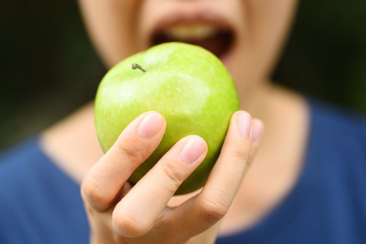 Midsection of woman eating granny smith apple