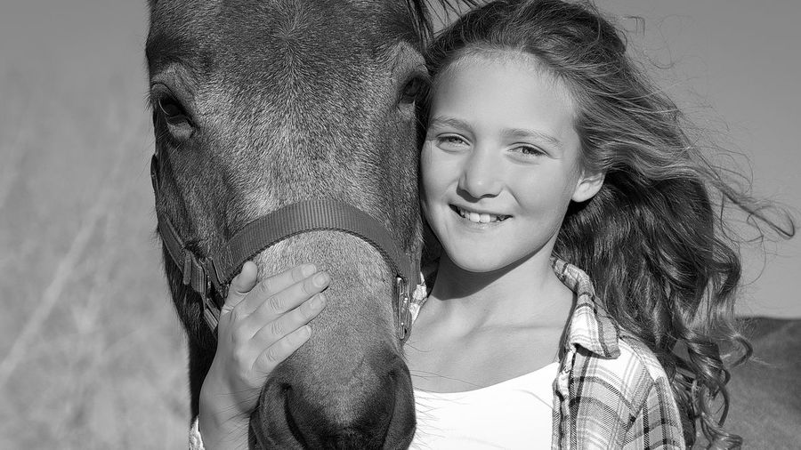 Portrait of smiling girl with horse outdoors