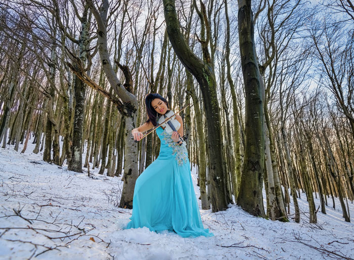 Woman playing on violin in the forest