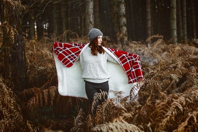 Woman with blanket standing on field during winter
