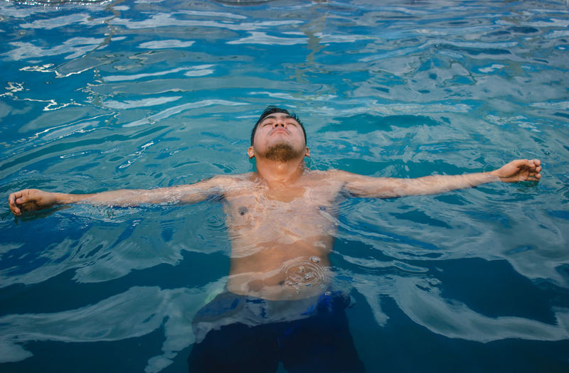 Full length of shirtless man swimming in pool