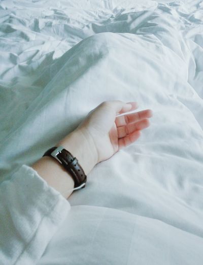 High angle view of cropped hand on bed