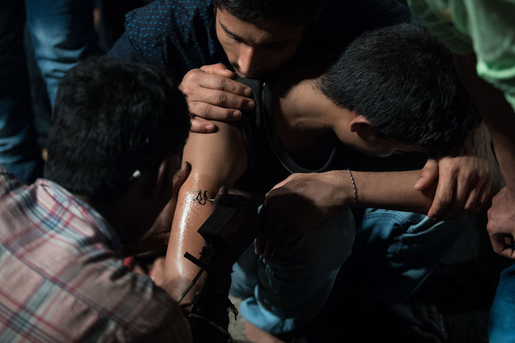 Male artits making tattoo on boy hand