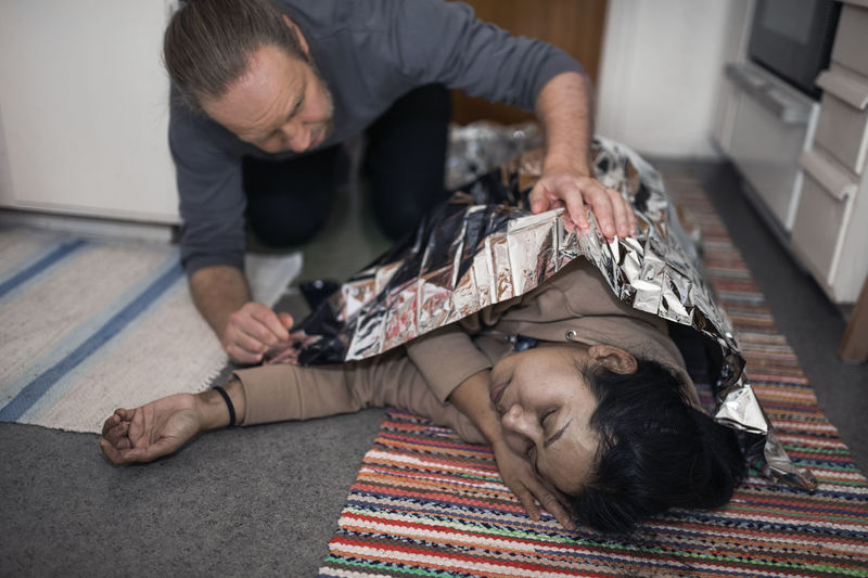 Man taking care of unconscious woman in medical shock