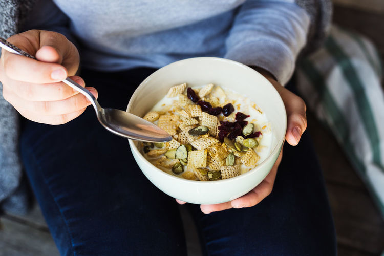 Midsection of woman holding bowl while sitting at home