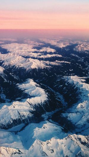 Aerial view of snowcapped mountains against sky during sunset