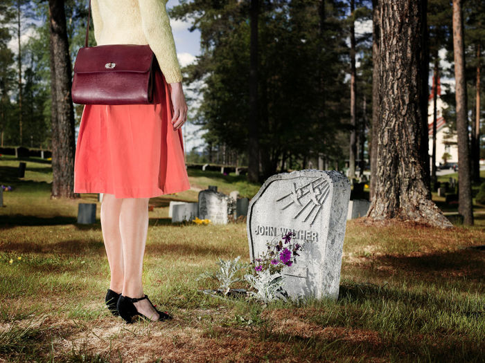 Low section of woman standing at cemetery