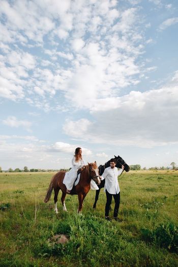 Couple riding horse on field